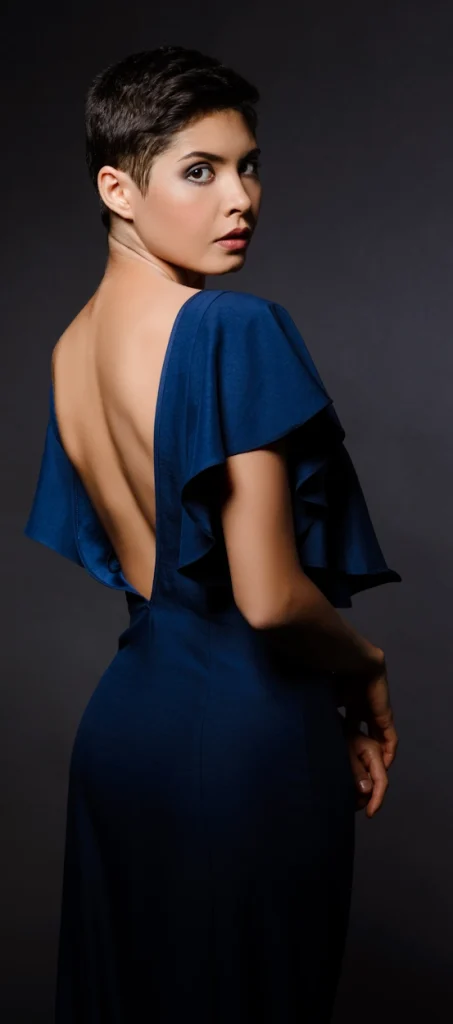 Жінка у вечірній сукні з відкритою спиною дивиться через плече, демонструючи ідеальну спину після пластики