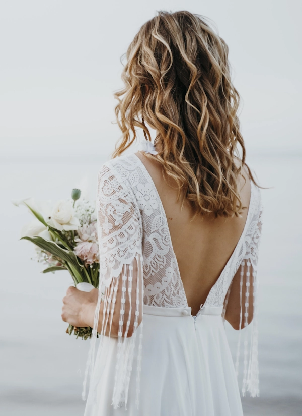 Наречена у сукні з відкритою спиною тримає букет, демонструючи гладку й рівну спину після пластики