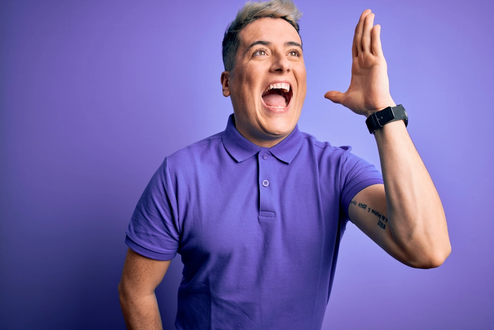 Радісний чоловік у фіолетовій сорочці поло з жестом вигуку — символ впевненості після обрізання крайньої плоті